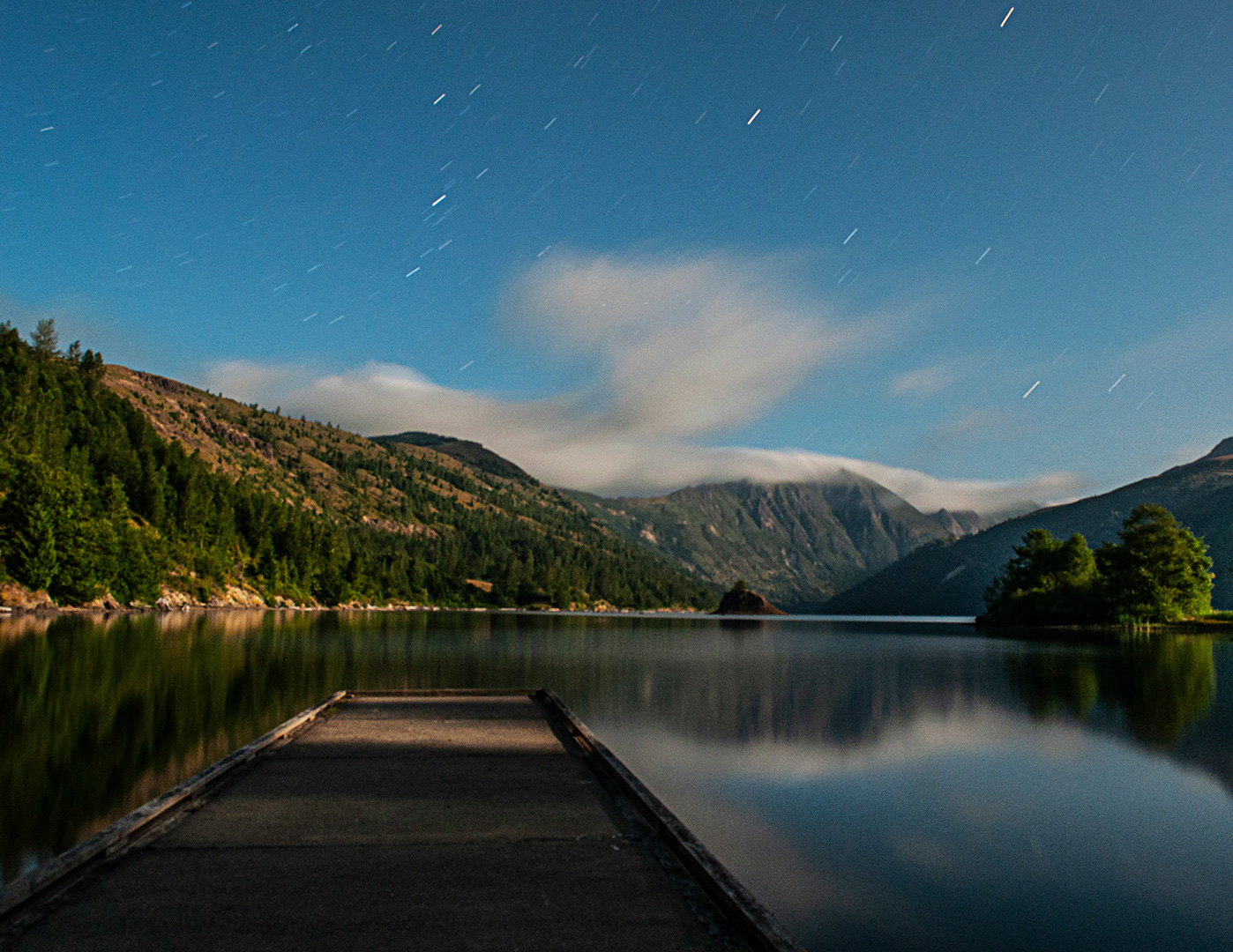 The boat dock at Coldwater lake juts into calm water below a clear starry sky.