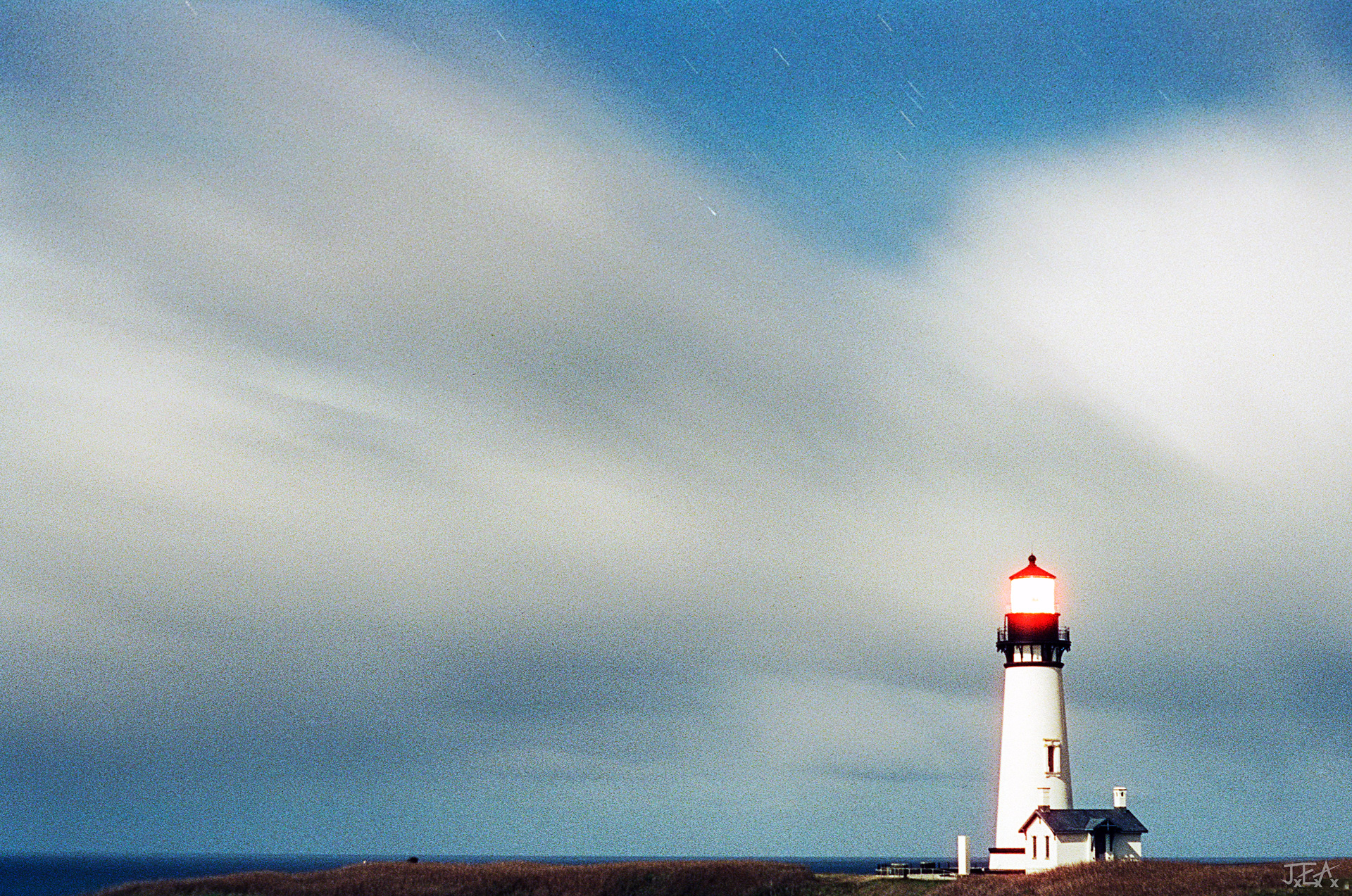 A wide angle view of the Yaquina Head Lighthouse in Newport, Oregon with an aproaching storm behind it.